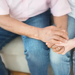 An older couple are seen sitting together, holding hands